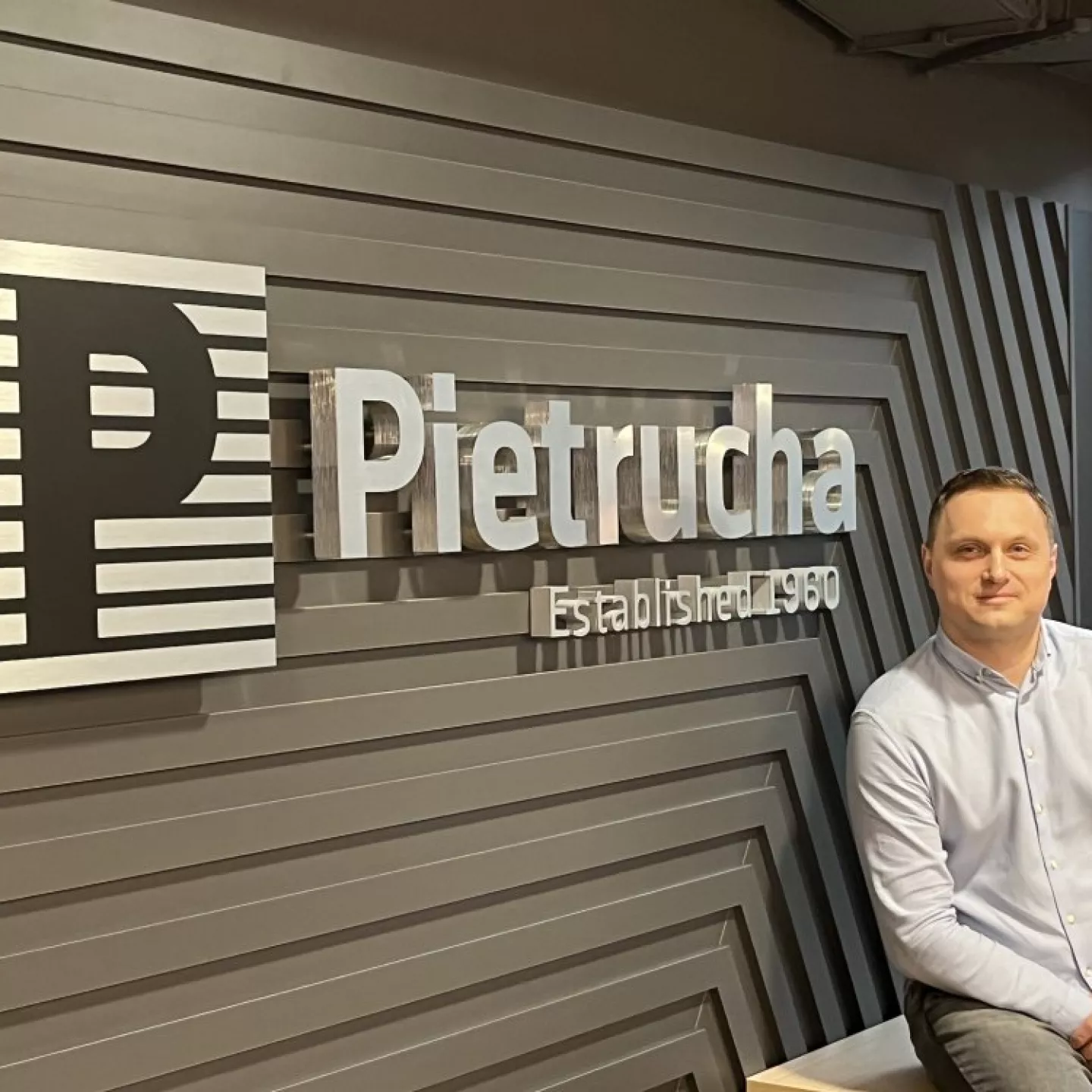 Mężczyzna siedzi na tle loga Pietrucha.