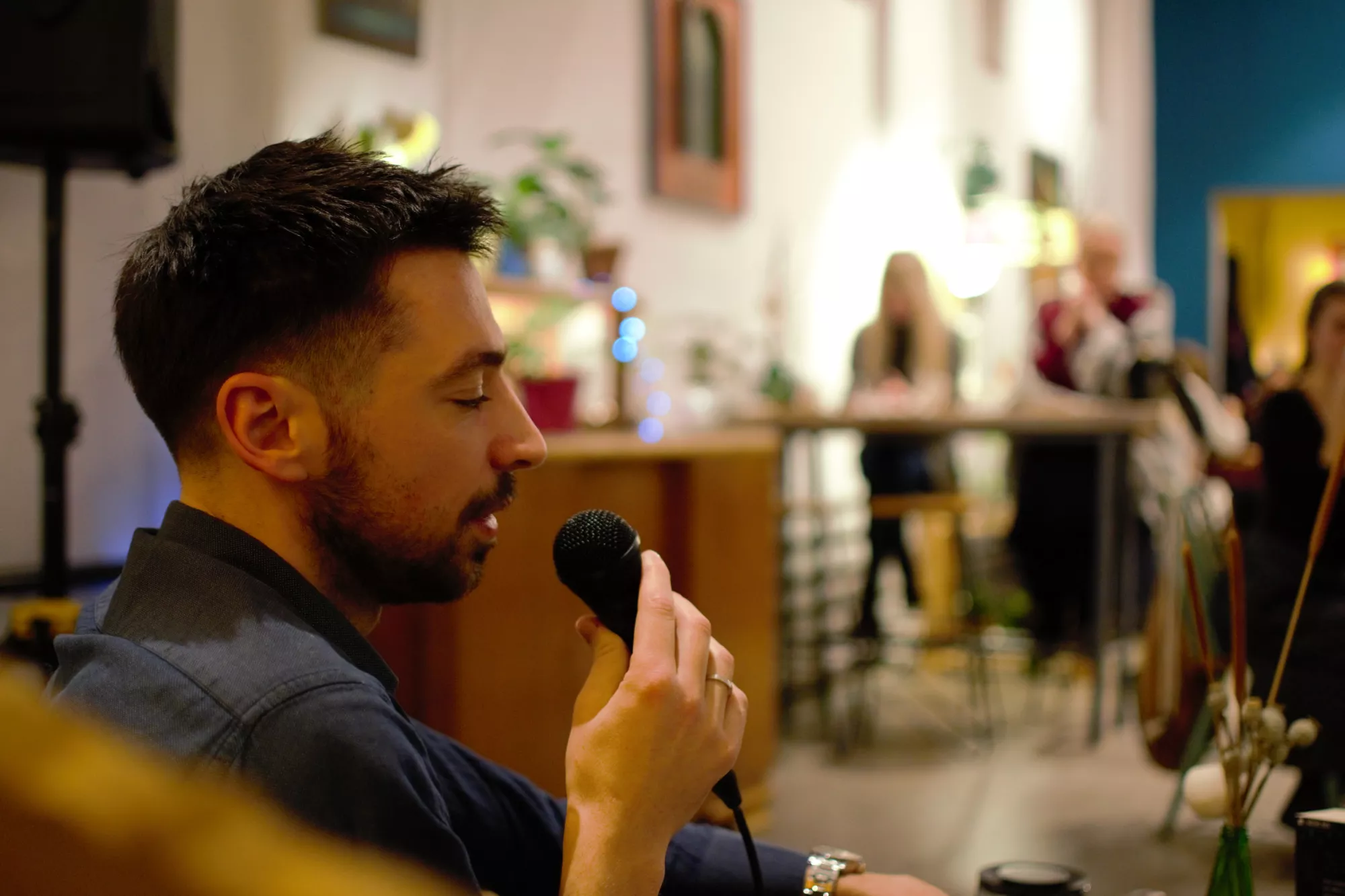 Mężczyzna śpiewa do mikrofonu w kawiarni.