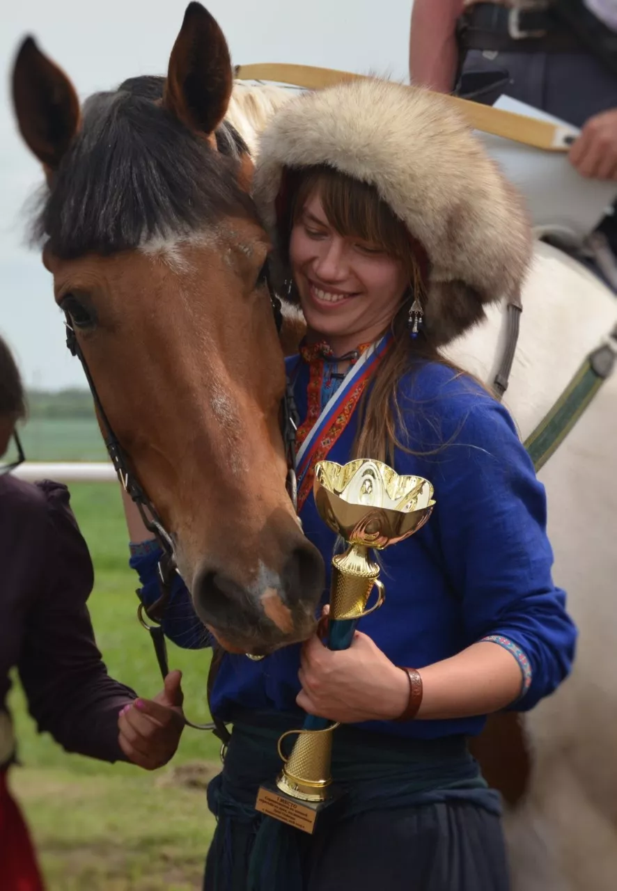 Kobieta przytula konia, trzymając trofeum.