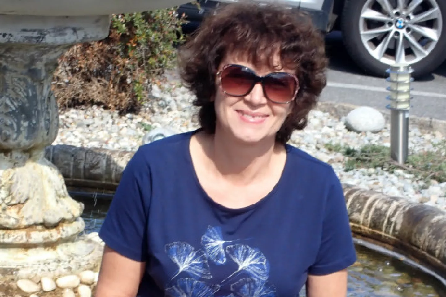 Kobieta siedzi na tle fontanny.