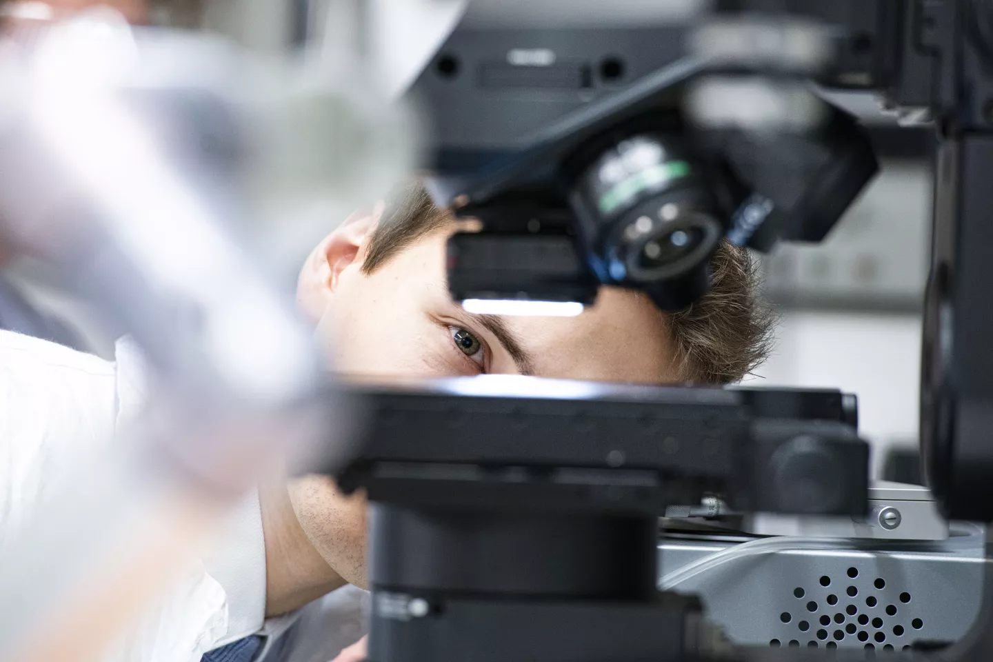 Mężczyzna zagląda pod mikroskop.