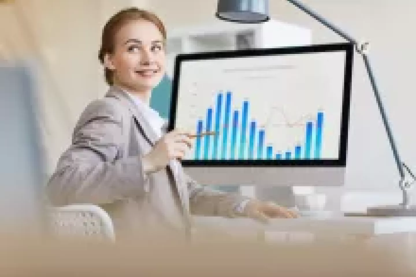 Uśmiechnięta kobieta przed monitorem z wykresami.