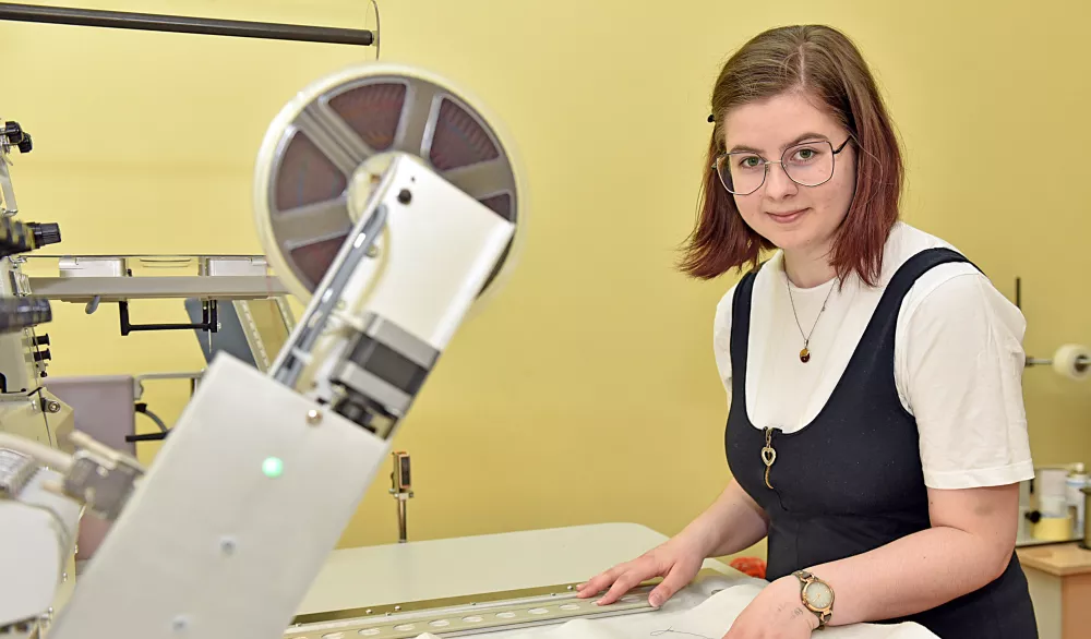 Kobieta obsługuje maszynę włókienniczą.