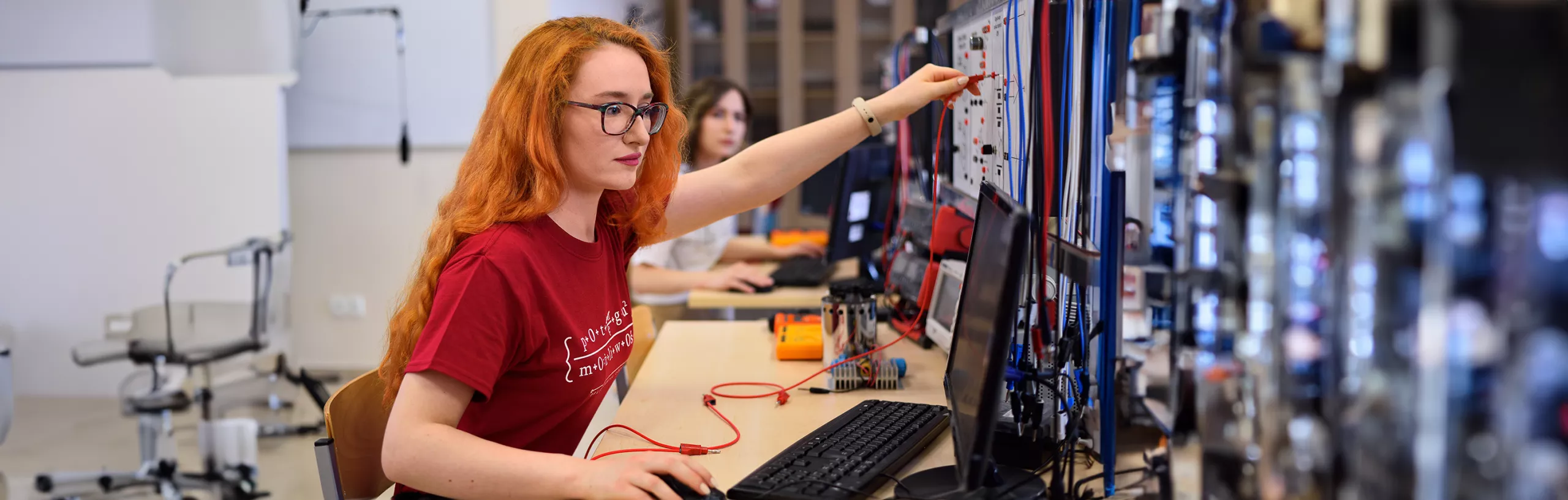 Studentka siedzi przy urządzeniu w laboratorium. 