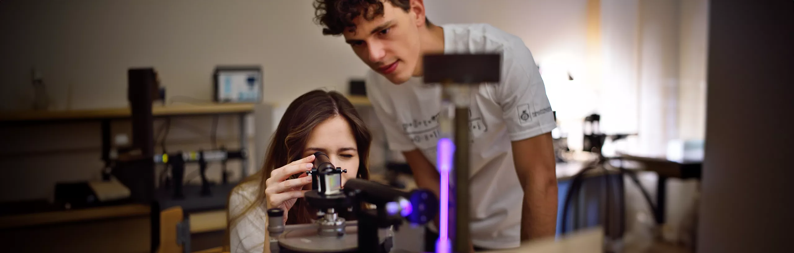 Studenci pracują na urządzeniu w sali zajęciowej.